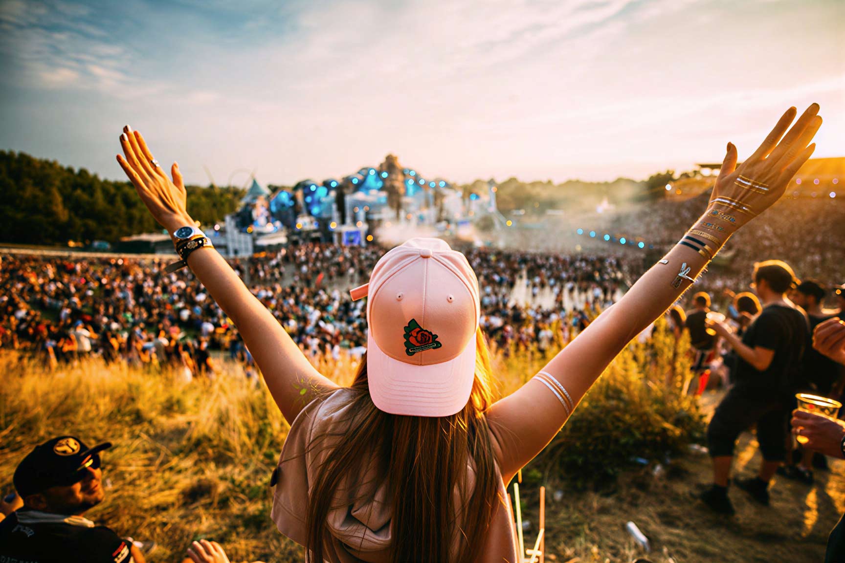 Festival-goer with arms raised facing the main stage
